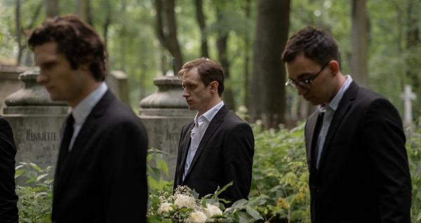 Three men dressed in suits at a funeral